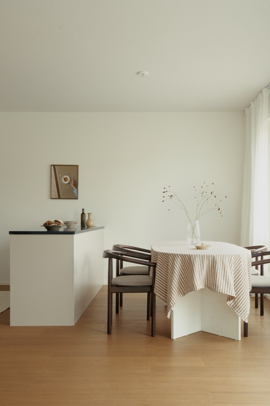 A light dining space with a linen-dressed table and a kitchen island