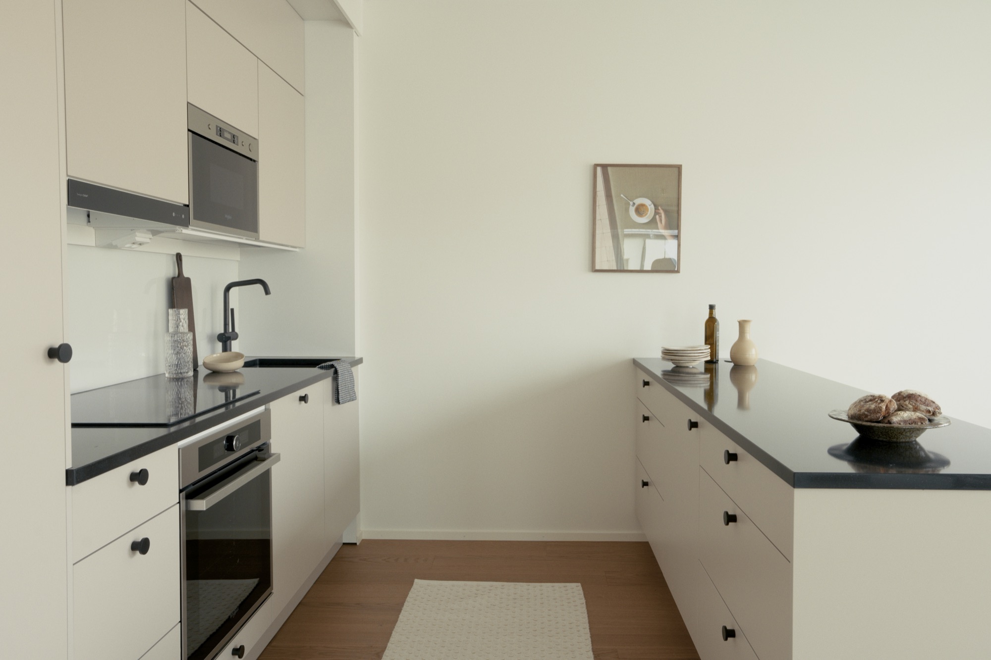A light kitchen with black worktops on a wood floor